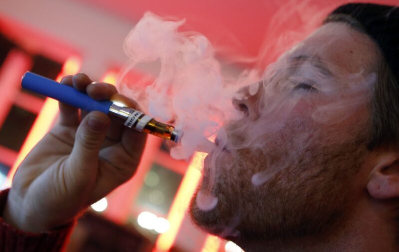 A customer puffs on an e-cigarette. Vape Cartridges Quality Concept