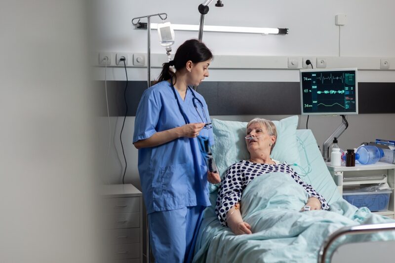 Nurse discussing with elderly patient during visit about chest x-ray