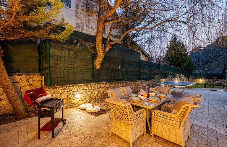 Inviting outdoor patio dining area with a table and barbecue grill at dusk