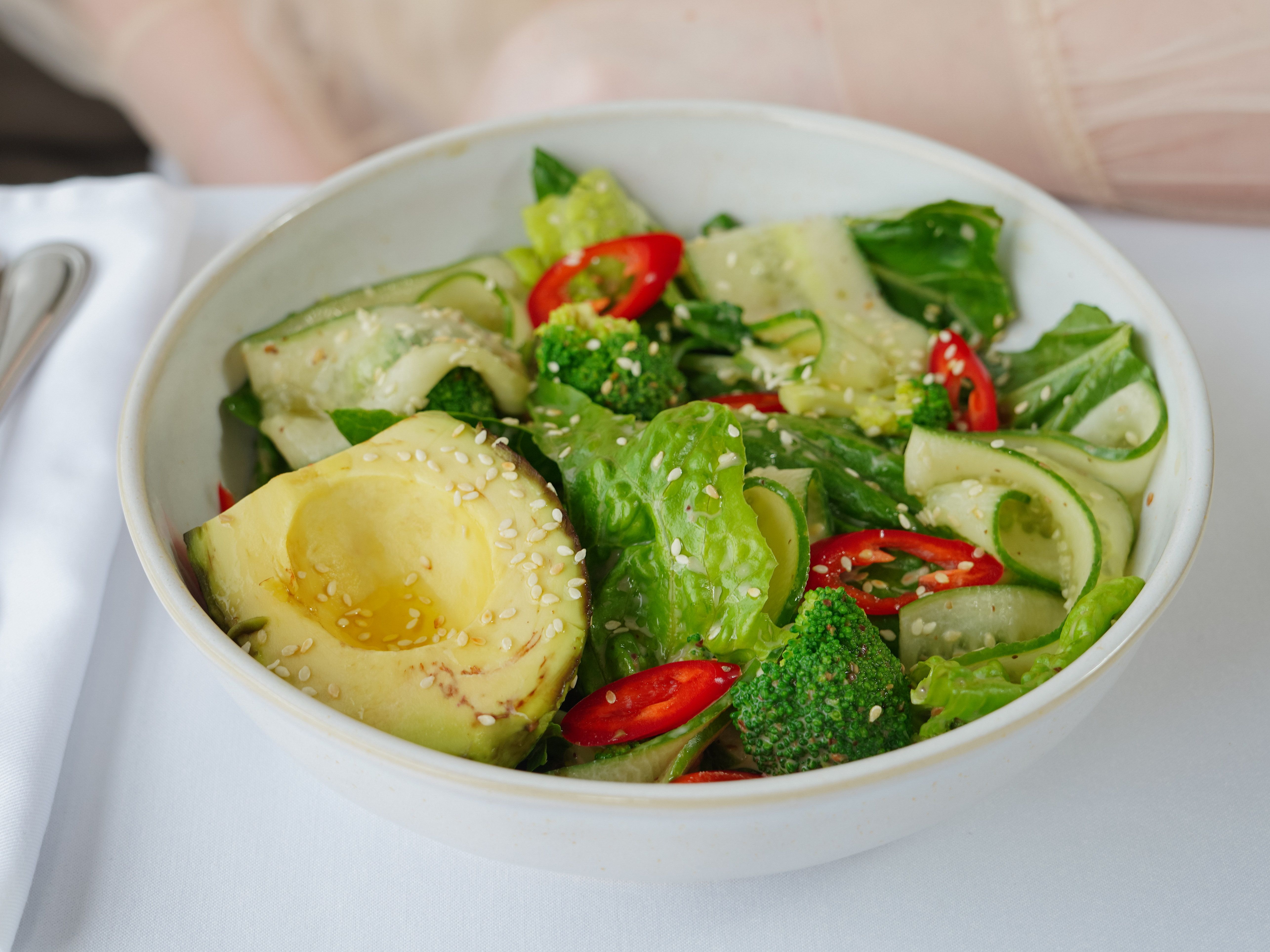 Colorful fresh vegetable salad with avocado, cucumber, broccoli, and sesame seeds